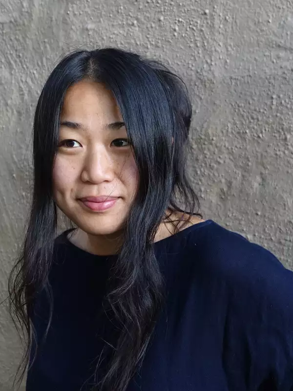 A woman of Chinese descent with long black hair and clad in a black top.